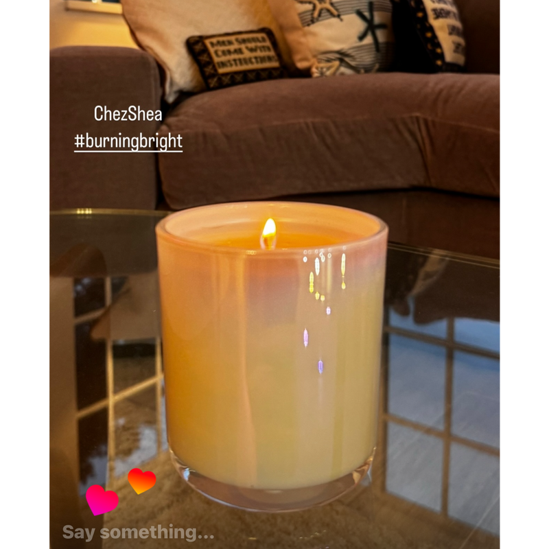 Candle on a coffee table with a couch and pillows in the background